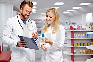 Two caucasian pharmacists are discussing medication, using a digital tablet