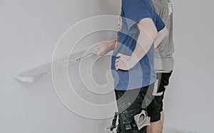 Two Caucasian plasterer man checks the evenness of the walls after puttying.
