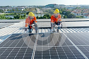 Two Caucasian technician workers hold document pad and tablet check and maintenance the solar panels on rooftop of the building or