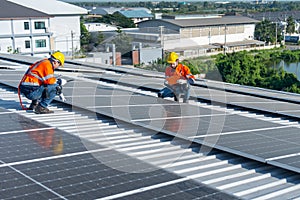 Two Caucasian technician workers sit on rooftop area to check and maintenance the solar cell panels on rooftop of factory or the