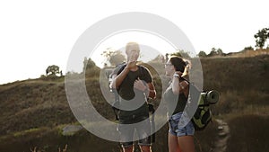 Two caucasian trevellers taking rest on a hill during their hiking. Take of the backpacks and sit on the ground