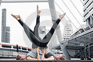 Two caucasian yoga partners having yoga workout outdoor in city