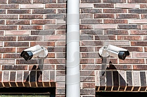 Two cctv surveillance security system cameras on the brick wall of luxury residential building for safety