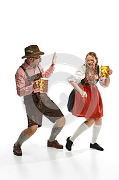 Two celebrating friends. Full lenght portrait of emotional man and woman wearing folk festival outfits, having glasses