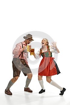 Two celebrating friends. Shouting man and woman wearing traditional German outfits, having clinking glasses with