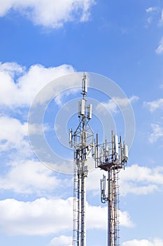 Two cell towers against the blue sky with clouds. Mobile communications, telephone network and communications.