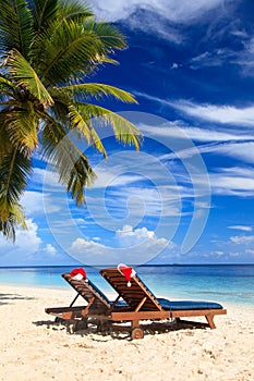 Two chair lounges with red Santa hats on beach