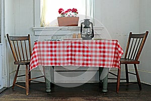 Two chairs at the ends of a rustic table with red checkered tablecoth