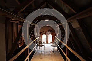 Two chairs in front of the windows among the timber joists in the attic of an old house