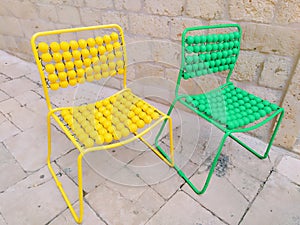 Two chairs are lined up on the marble pavement. Yellow and green empty massage chairs with pimples. Dubrovnik, Croatia