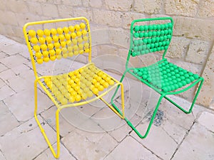 Two chairs are lined up on the marble pavement. Yellow and green empty massage chairs with pimples. Dubrovnik, Croatia