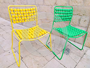 Two chairs are lined up on the marble pavement. Yellow and green empty massage chairs with pimples. Dubrovnik, Croatia