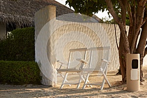 Two chairs near spa bungalow center on tropical island in Maldives at exotic resort on the white sand beach