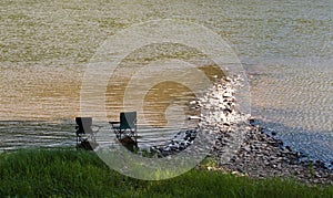 Two chairs sitting in the shade in a river