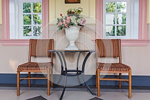 Two chairs and table with bouquet of flowers in vase on a patio