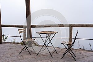 Two chairs and a table on a terrasse in the fog, vesuv mountain, italy