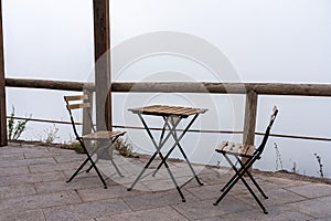 Two chairs and a table on a terrasse in the fog, vesuv mountain, italy