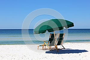 Two chairs and umbrella on white sand beach