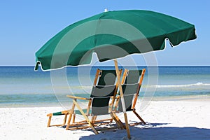 Two chairs and umbrella on white sand beach