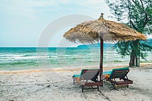 Two chaise lounges and straw umbrella on tropical beach. Coast of island Koh Rong Samloem