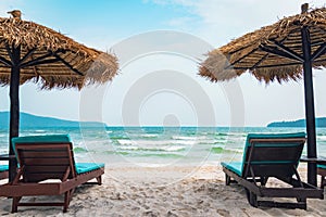 Two chaise lounges and straw umbrella on tropical beach. Coast of island Koh Rong Samloem. free empty copy space for text