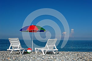 Two chaise lounges and umbrella on a beach