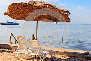 Two chaise lounges under a sun umbrella on tropical beach. Concept of rest, relaxation, holidays, resort