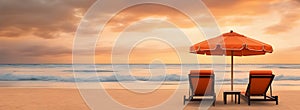 A two chaise lounges under an umbrella on the shore sandy beach, on a sunset background, beautiful orange clouds