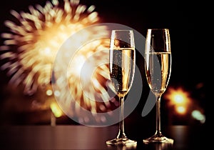 two champagne glasses against holiday lights and fireworks - new year celebration