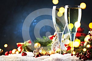 Two champagne glasses and christmas decoration over blue snow golden bokeh background. Happy New Year Celebration. Selective focus