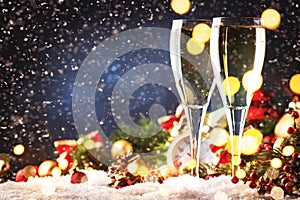 Two champagne glasses and christmas decoration over blue snow golden bokeh background. Happy New Year Celebration. Selective focus