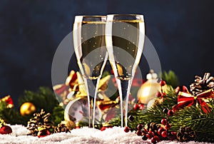 Two champagne glasses and christmas decoration over blue snow golden bokeh background. Happy New Year Celebration. Selective focus