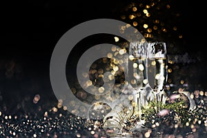Two champagne glasses and christmas decoration over dark golden bokeh background