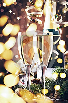 Two champagne glasses and christmas decoration on wooden snow golden bokeh background. Happy New Year Celebration. Selective focus