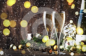 Two champagne glasses and christmas decoration on wooden snow golden bokeh background. Happy New Year Celebration. Selective focus