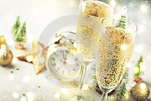 Two champagne glasses with moving bubbles and christmas decoration over gray golden bokeh background. Happy New Year Celebration.