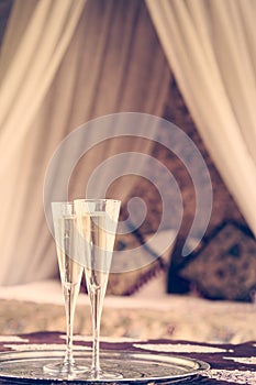 Two champagne glasses with oriental canopy bed at the background