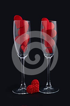 Two champagne glasses with red hearts for couple on black background. Happy valentines day dinner.