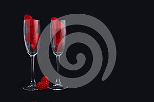 Two champagne glasses with red hearts for couple on black background. Happy valentines day dinner.