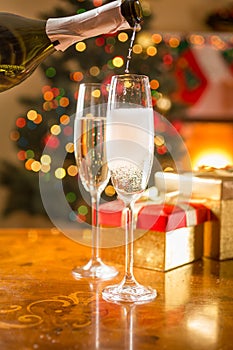 Two champagne glasses on table being filled from bottle