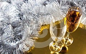 Two champagne or wine glasses with gold and silver christmas tinsel decoration.