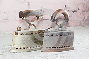 Two charcoal irons on table against background of the brickwork