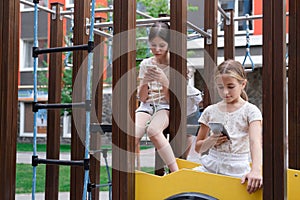 two charming teenage girls in identical clothes with smartphones outside. kids surf the net. smartphone addiction