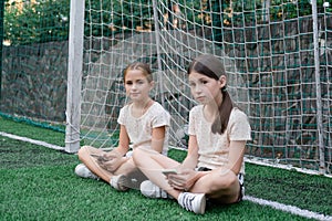 two charming teenage girls in identical clothes with smartphones outside. kids surf the net. smartphone addiction