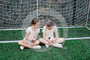 two charming teenage girls in identical clothes with smartphones outside. kids surf the net. smartphone addiction
