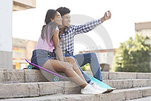 Two cheerful african teenagers taking selfie outdoors