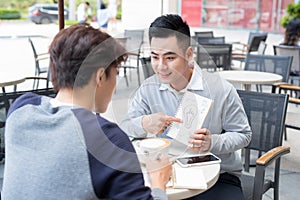 Two cheerful asian business people discussing with documents