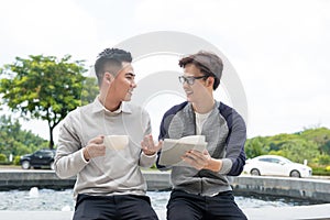 Two cheerful asian business people discussing with documents