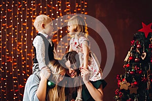 Two mothers sitting with cute kids christmas presents.