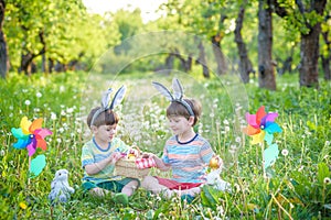 Two cheerful boys sit on the lawn after Easter eggs hunt
